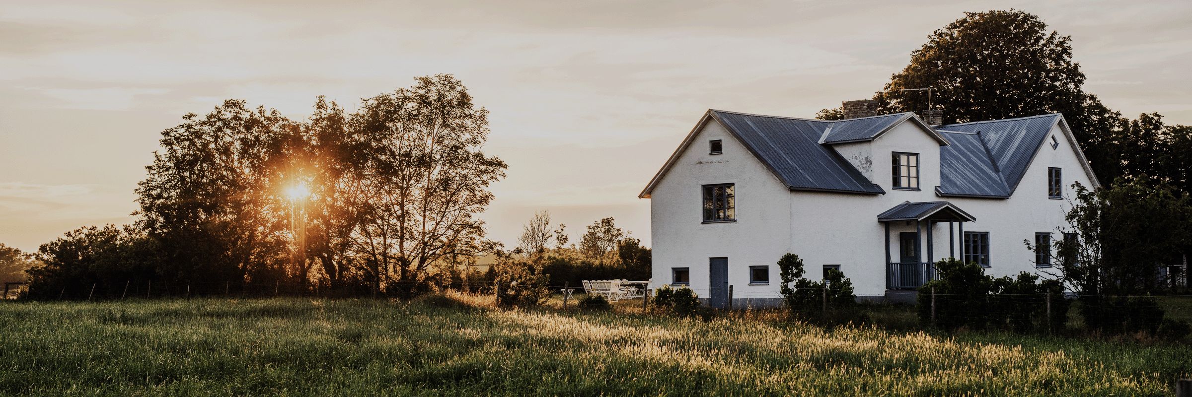 Vitt hus i puts i motljus på skånska landsbygden