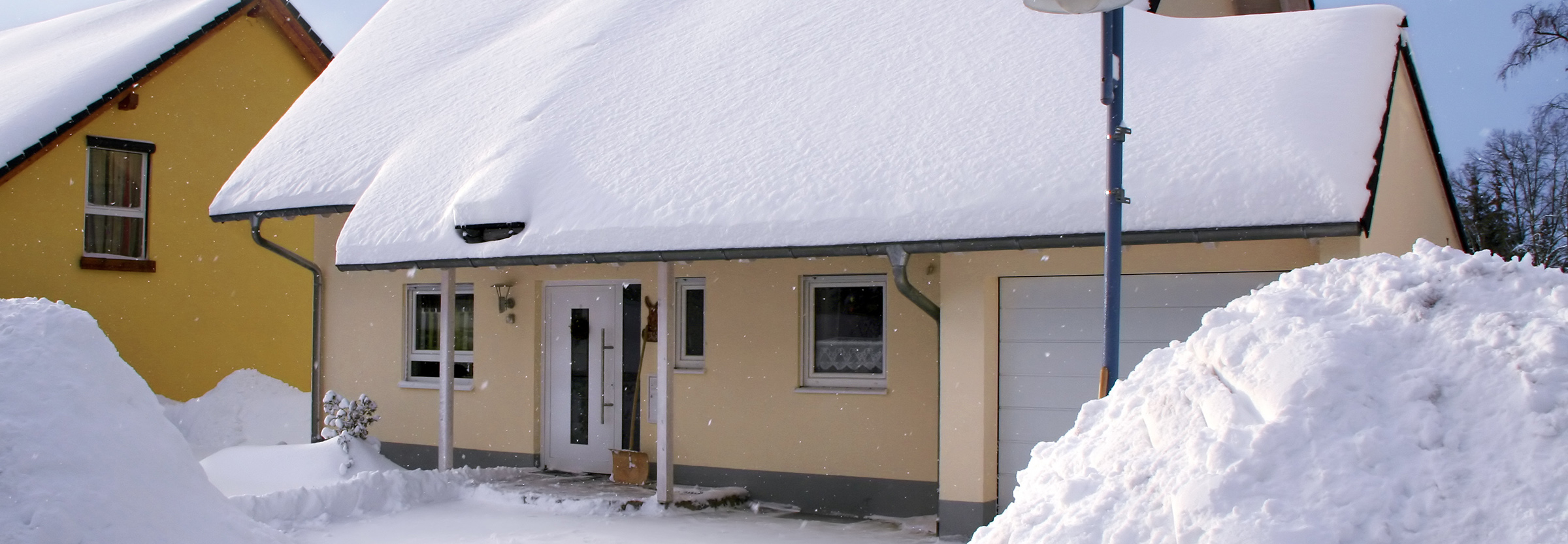 Gult hus med mycket snö på taket