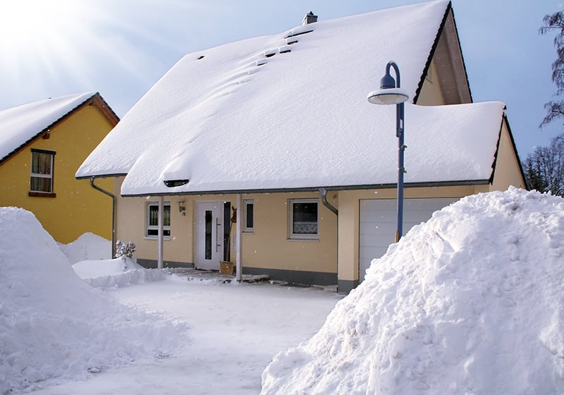 Gult hus med mycket snö på taket
