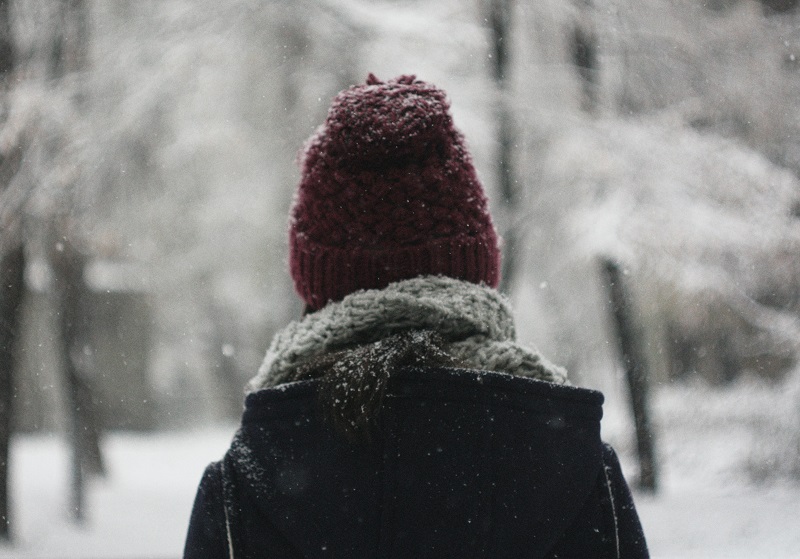 Person i mössa går i snölandskap