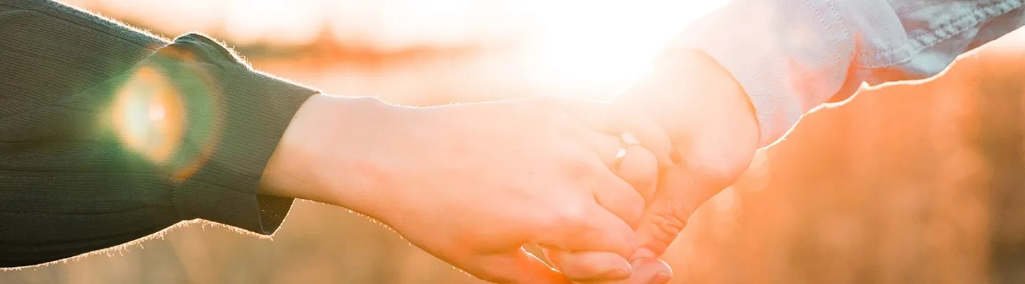 Par håller handen i solnedgången
