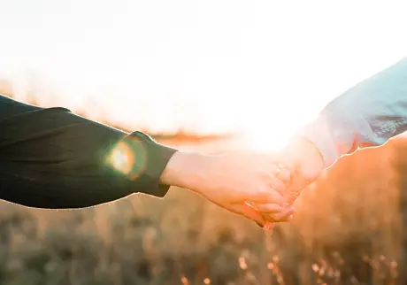 Par håller handen i solnedgången