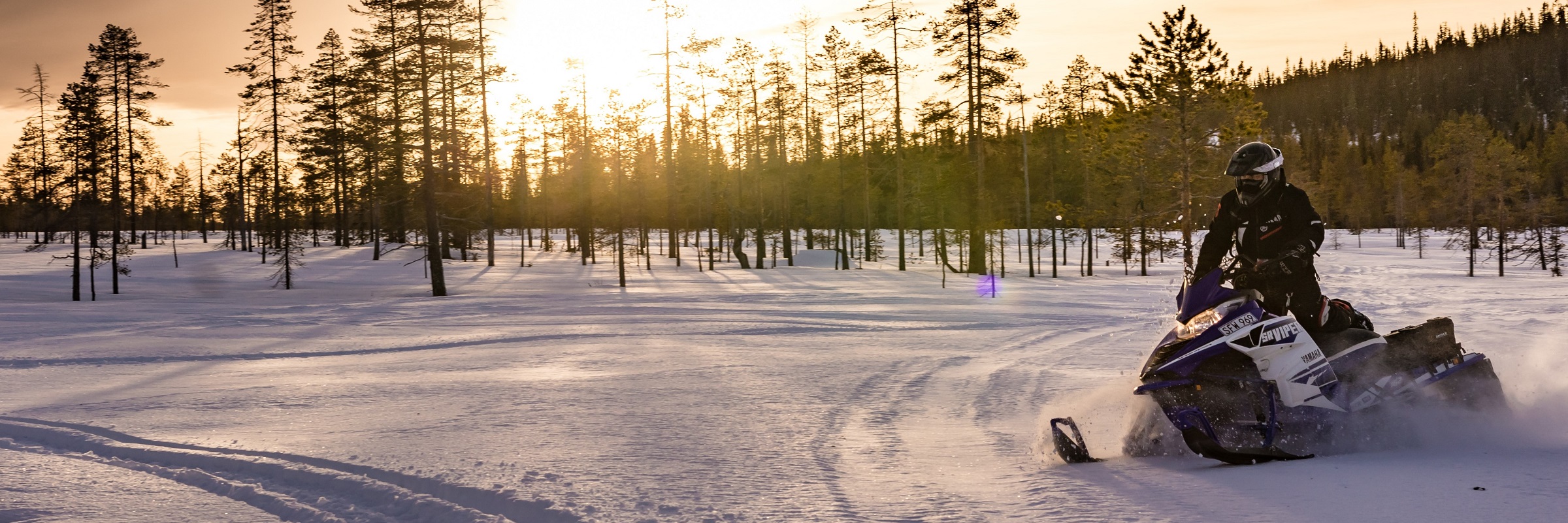 Snöskoter i fjällen med solnedgång