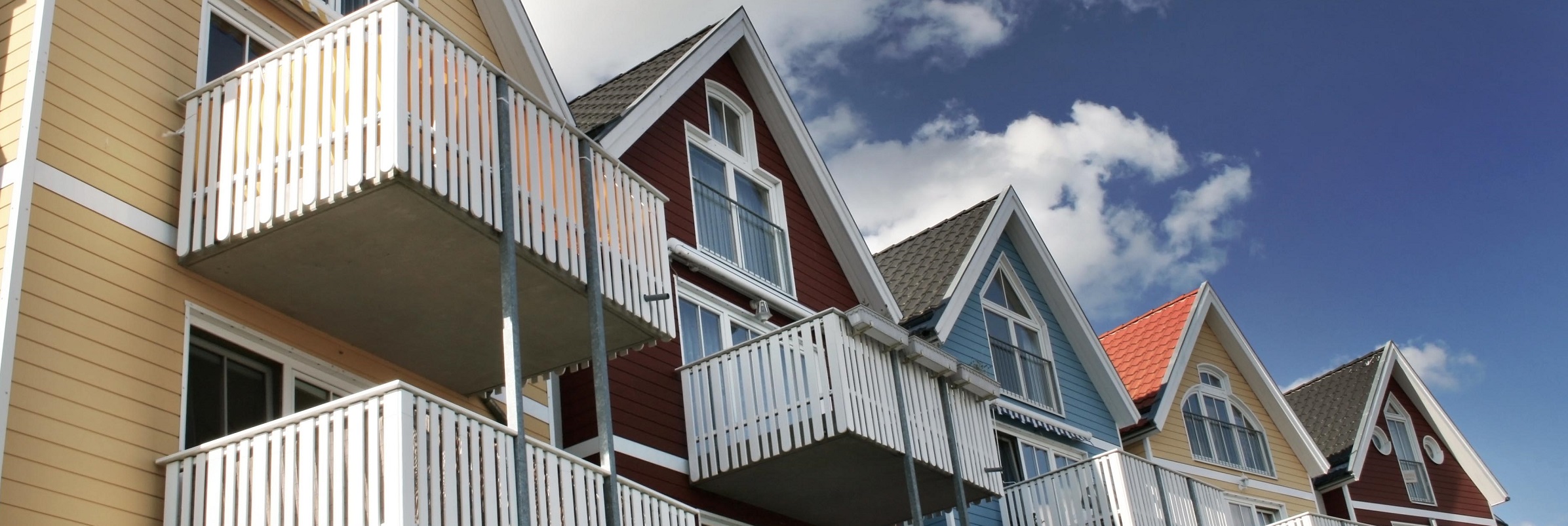 Flerfärgade hus med balkonger mot blå himmel