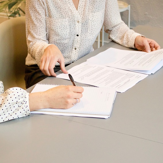 Två kvinnor antecknar och tittar på avtal