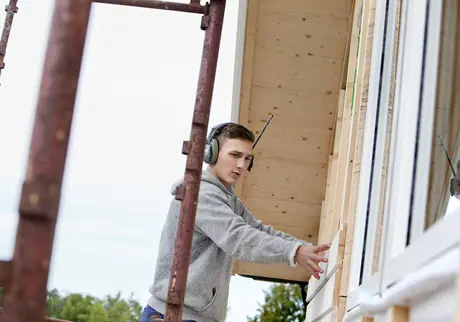 Hantverkare på byggnadsställning lägger plankor på hus