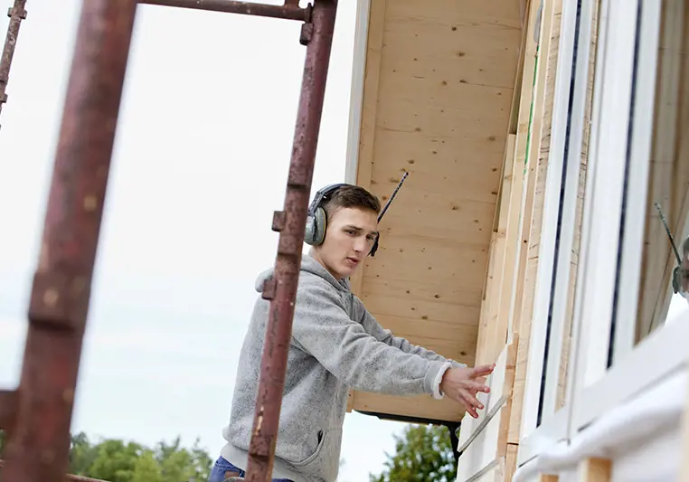 Hantverkare på byggnadsställning lägger plankor på hus