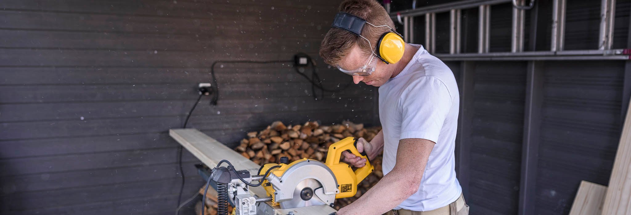 Man med elektrisk såg i carport