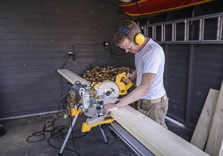 Man med elektrisk såg i carport
