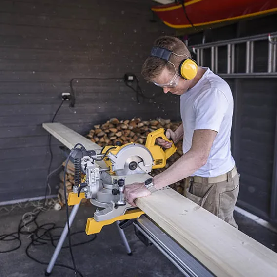 Man med elektrisk såg i carport