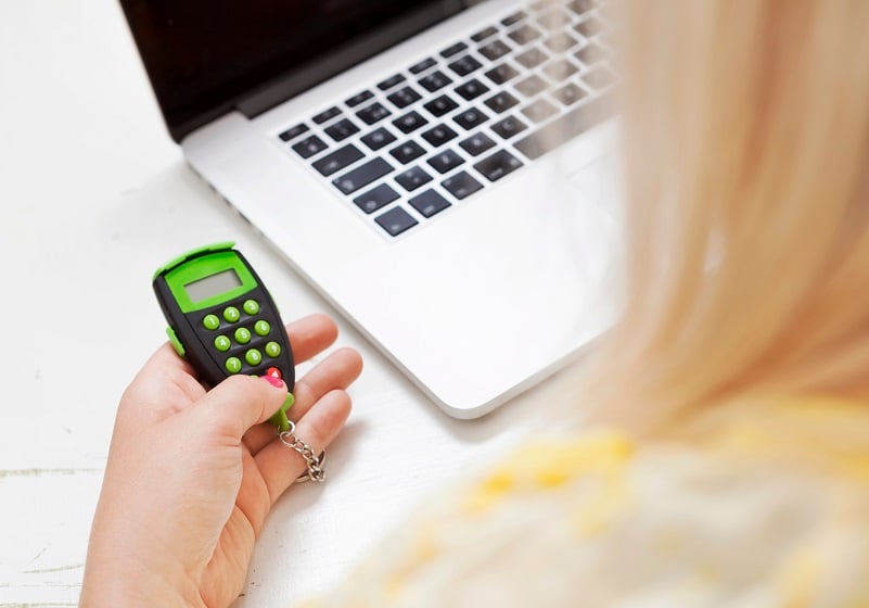 Kvinna håller i bankdosa bredvid laptop