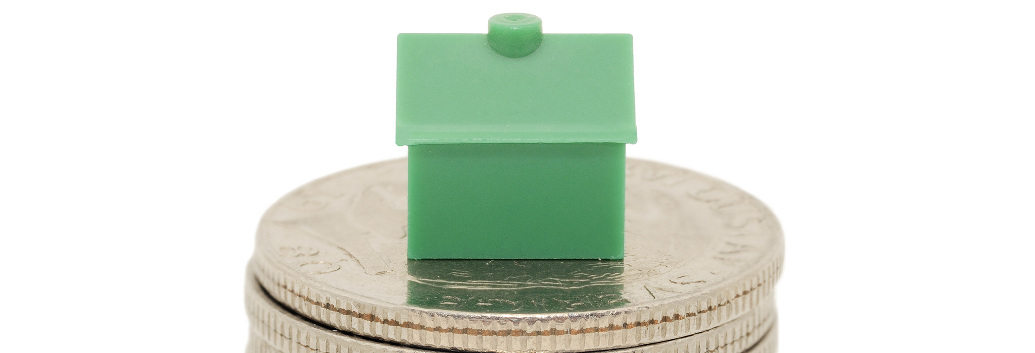 Grönt monopolhus på myntstapel