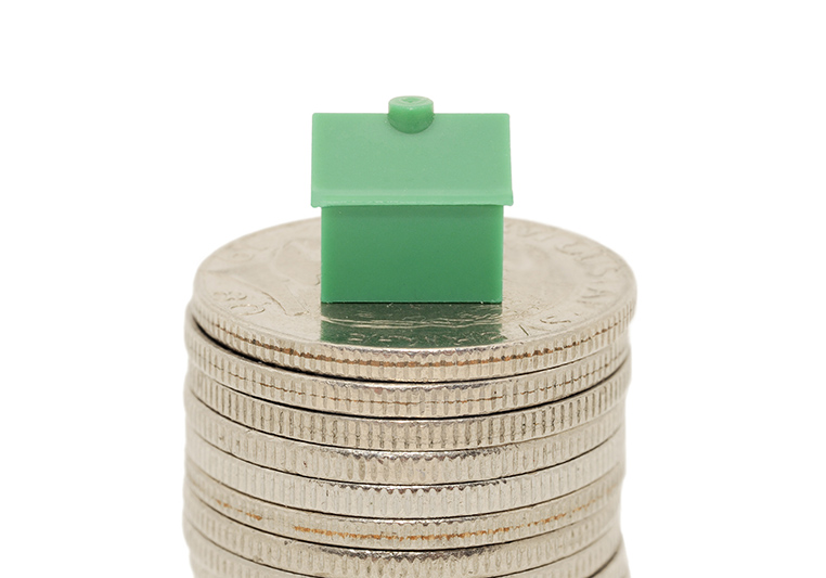 Grönt monopolhus på myntstapel