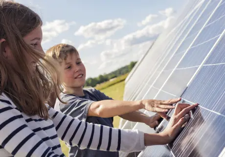 Två barn håller händerna på solpaneler