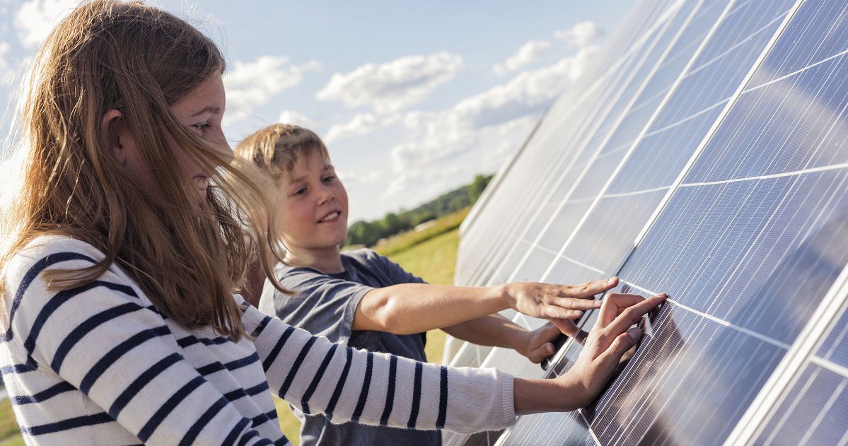 Två barn håller händerna på solpaneler