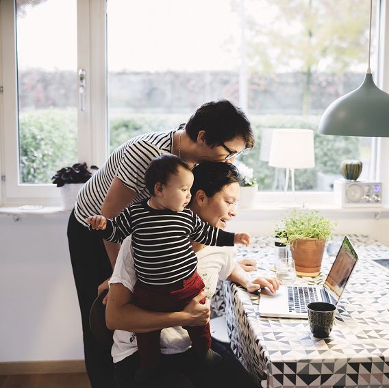 Familj i kök med spädbarn tittar på laptop