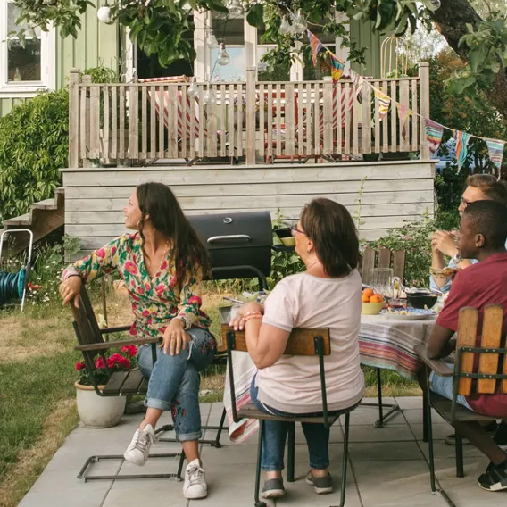 Familj i trädgården sitter i trädgårds medan dotter medan dotter sitter på pappas axlar