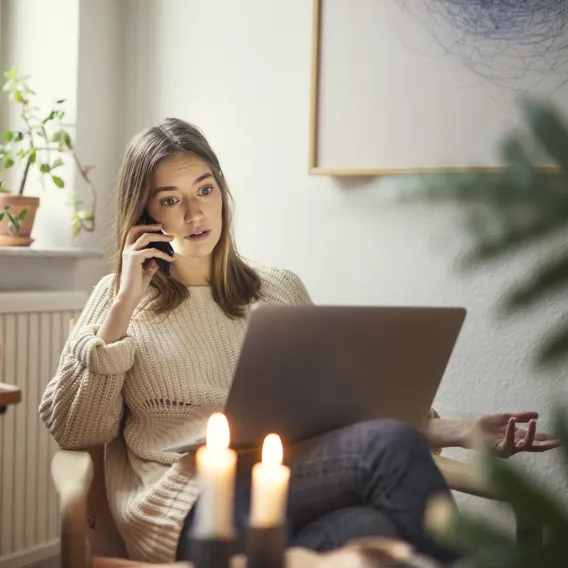 Kvinna pratar i telefon och använder laptop