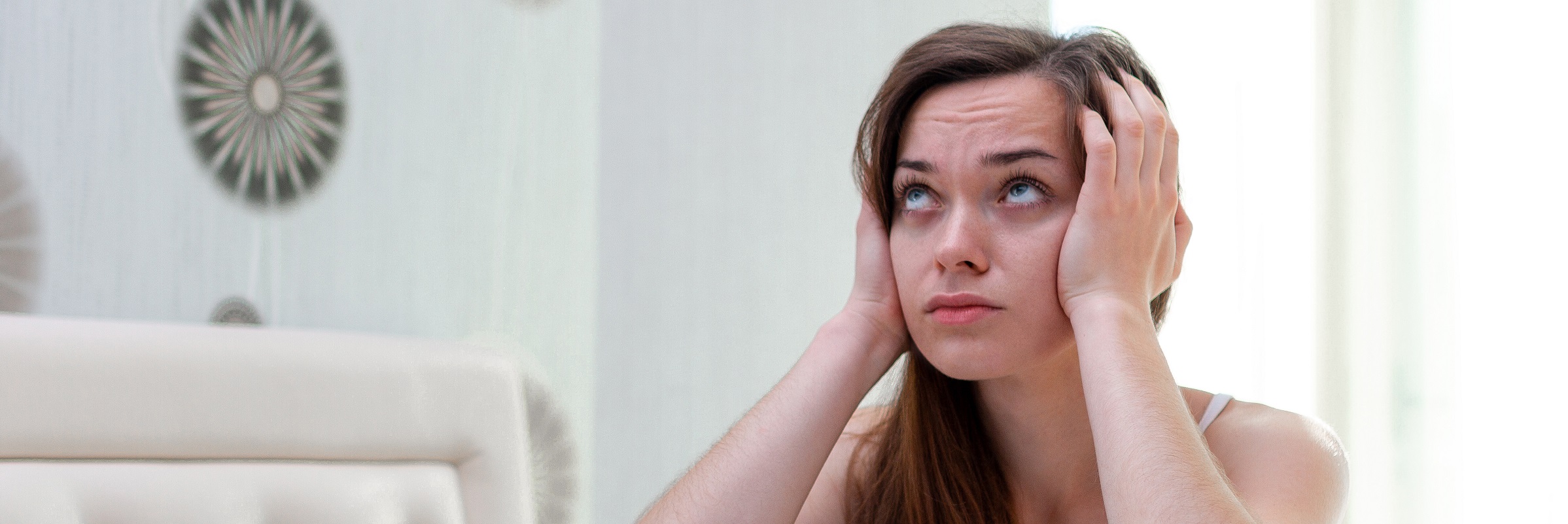 Kvinna sitter i sängen håller för öronen irriterat