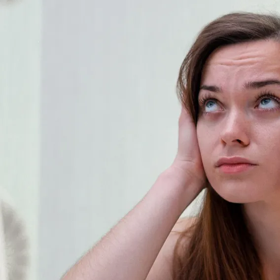 Kvinna sitter i sängen håller för öronen irriterat