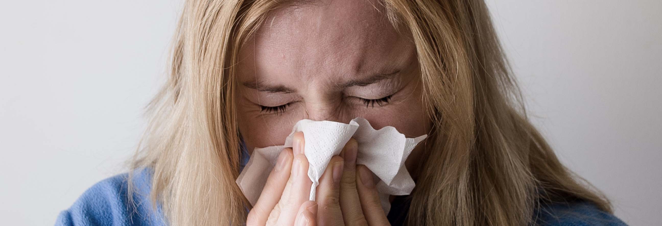 Kvinna nyser i pappersnäsduk