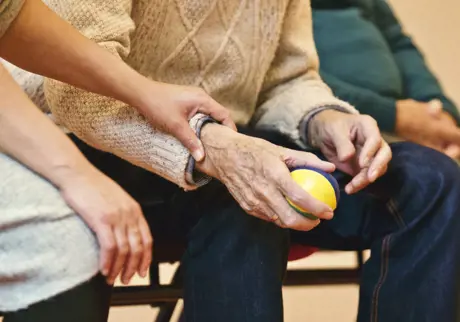 Kvinna håller i äldre mans hand som håller i en boll