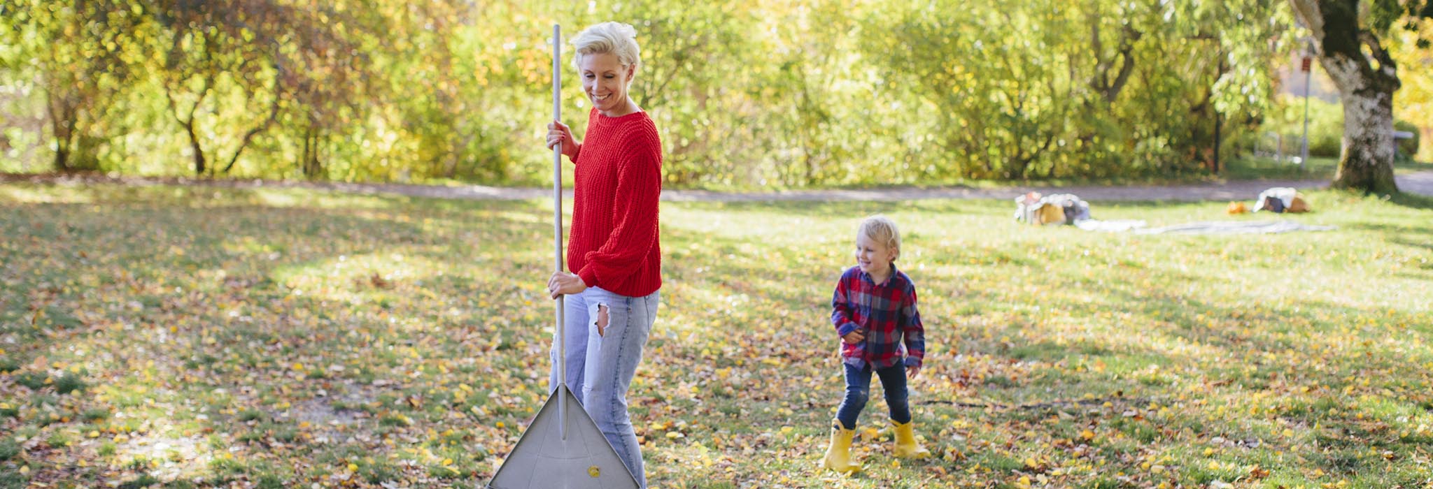 Kvinna krattar löv med barn