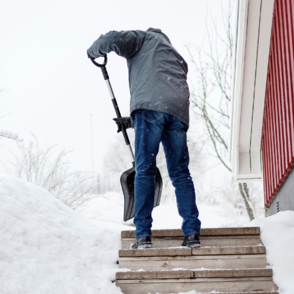 Man skottar bort snö vid trappa