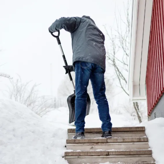Man skottar bort snö vid trappa
