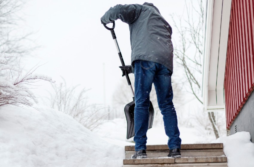 Man skottar bort snö vid trappa