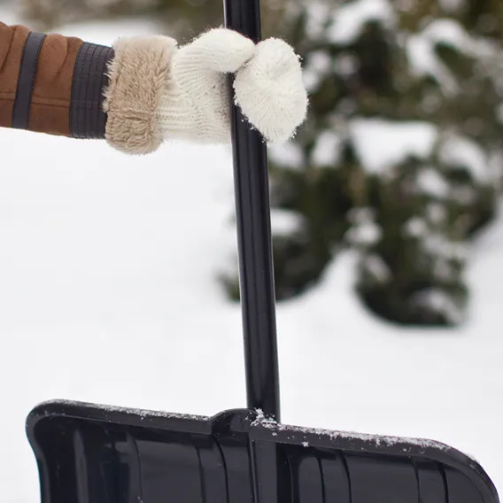 Hand ed vante på snöskyffel