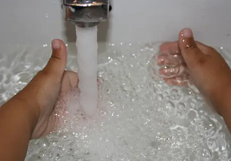 Barnhänder under vattenkran