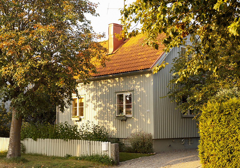 Höstbild med vit villa och vitt staket med träd utanför staketet