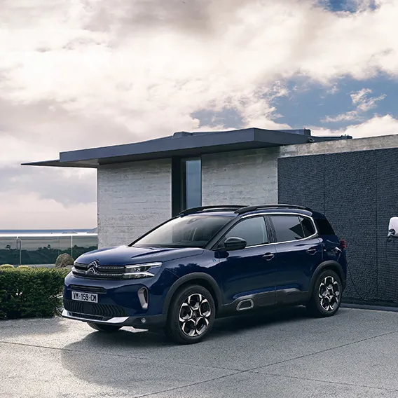 Blå Citroën under laddning invid husvägg