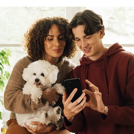 Kvinna, man och hund som kikar på en mobil