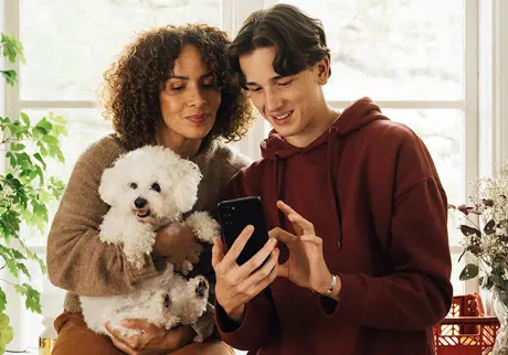kvinna man och hund som kikar på en mobil