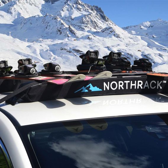 Takräcke med slalomskidor på vit bil i snölandskap