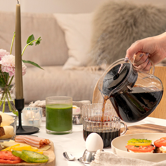 Frukost på bordet med hand som häller i kaffe