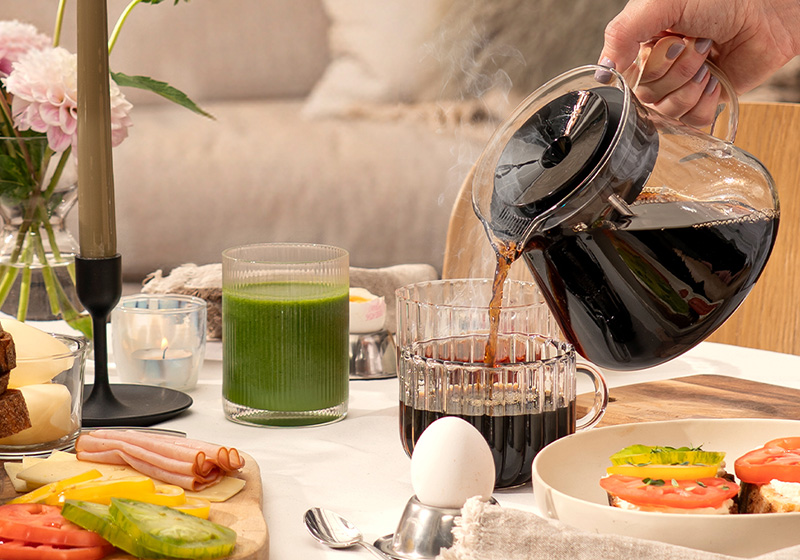 Frukost på bordet med hand som häller i kaffe