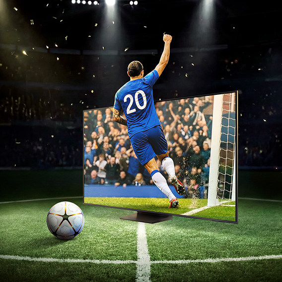 Fotbollsspelare med segergest, fotboll och TV på fotbollsplan