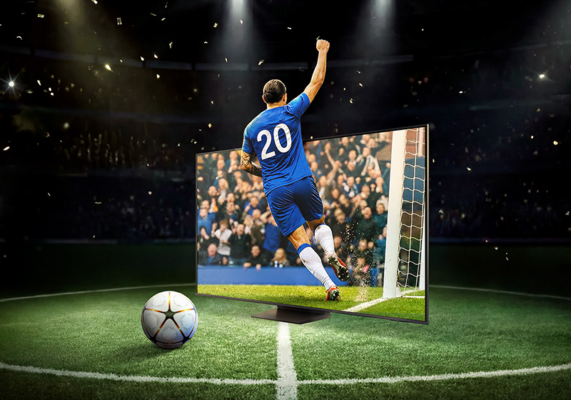 Fotbollsspelare med segergest, fotboll och TV på fotbollsplan