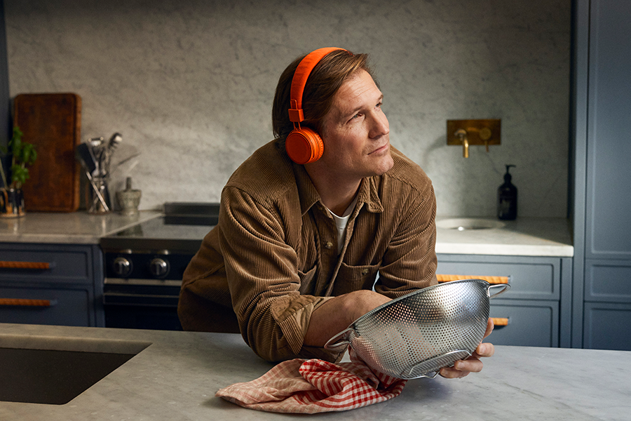 Man som står i köket och torka disk och lyssnar på ljudbok