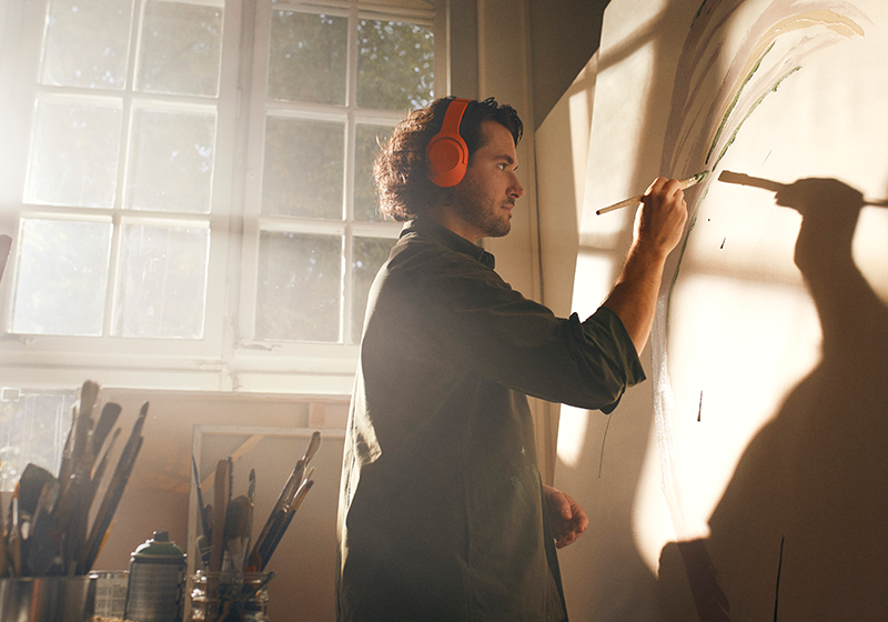 Kille som står och målar samt lyssnar på en ljudbok